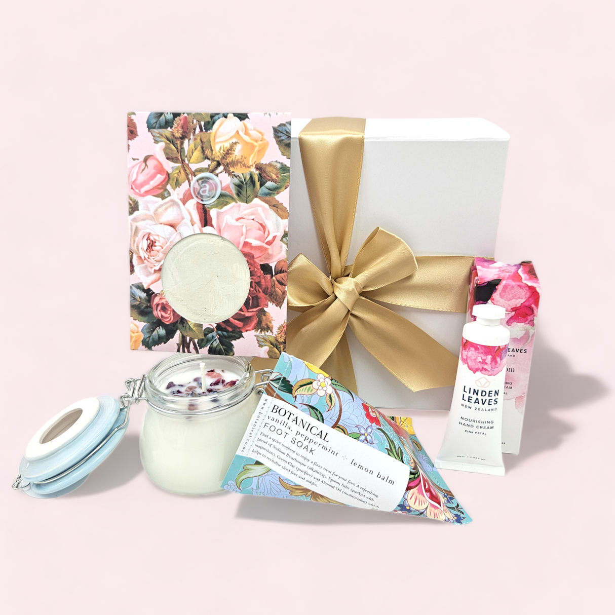 Relaxation gift box in pink featuring calming items: aromatherapy candle, hand cream, facial mask, and foot soak.