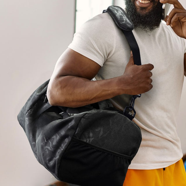 Camouflage duffle bag with shoe compartment, featuring spacious main pocket, adjustable straps, and sturdy carry handles.