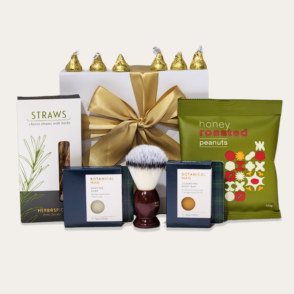 Luxurious grooming gift box for men featuring premium cleansing bar, bath bomb, shaving soap, brush, cheese straws, and elegant packaging.