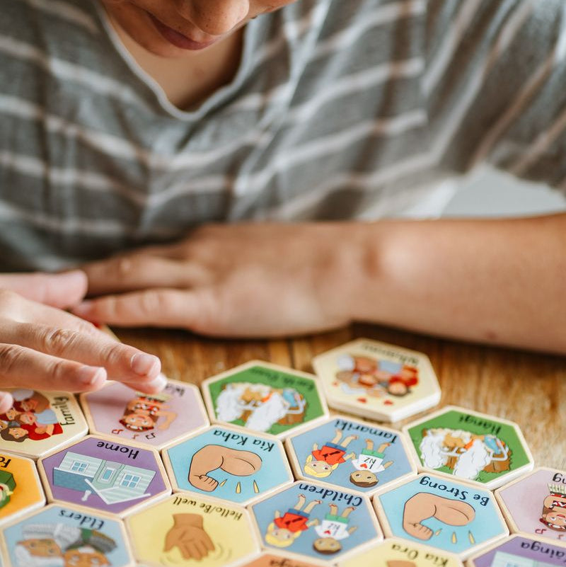 Colorful hexagon-shaped tiles featuring Te Reo and English words for a bilingual memory game for children.