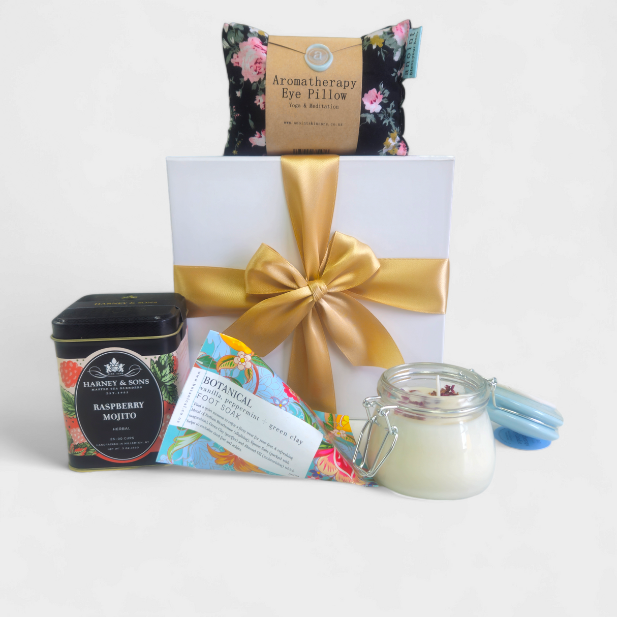 Elegant gift box with relaxation items: foot soak, tea, eye pillow, and candle for a serene experience.