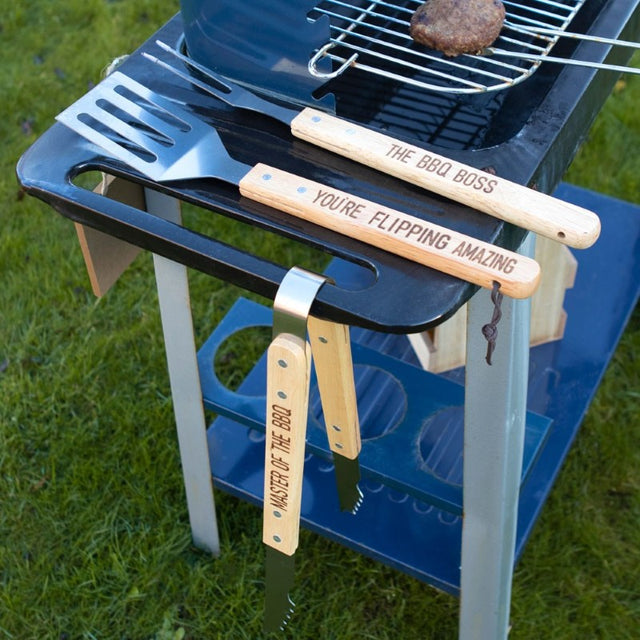 3 Piece BBQ Tool Set in a metal case featuring stainless steel tools with wooden handles and motivational phrases for grilling fun.