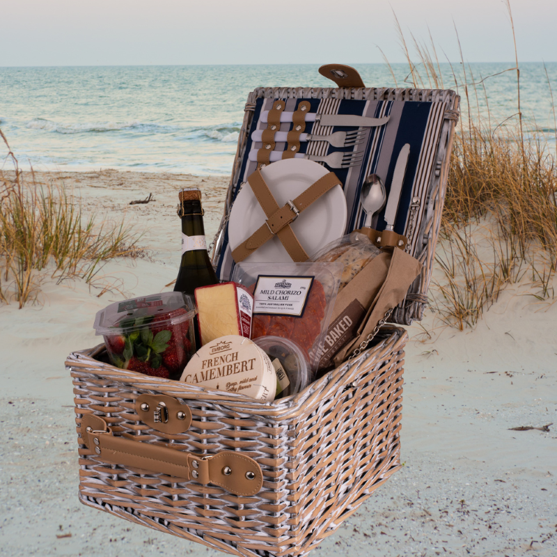 Stylish 2-person picnic basket with Hampton Stripe lining, includes utensils, plates, and goblets for outdoor dining.