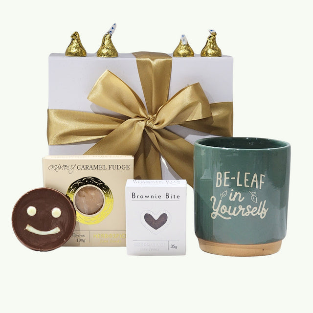 A beautifully packaged gift box with uplifting items, including a planter pot, fudge, chocolate, and a ribbon.
