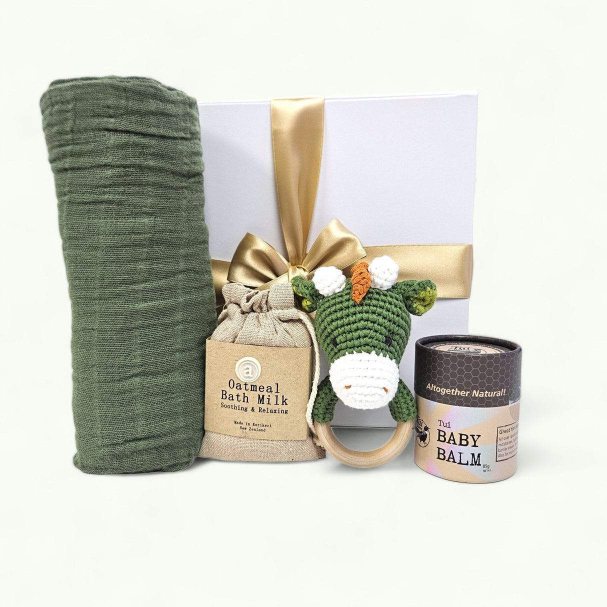 Luxurious baby gift box featuring a dino theme, including bath milk, swaddle, rattle, and soothing balm for ultimate comfort.
