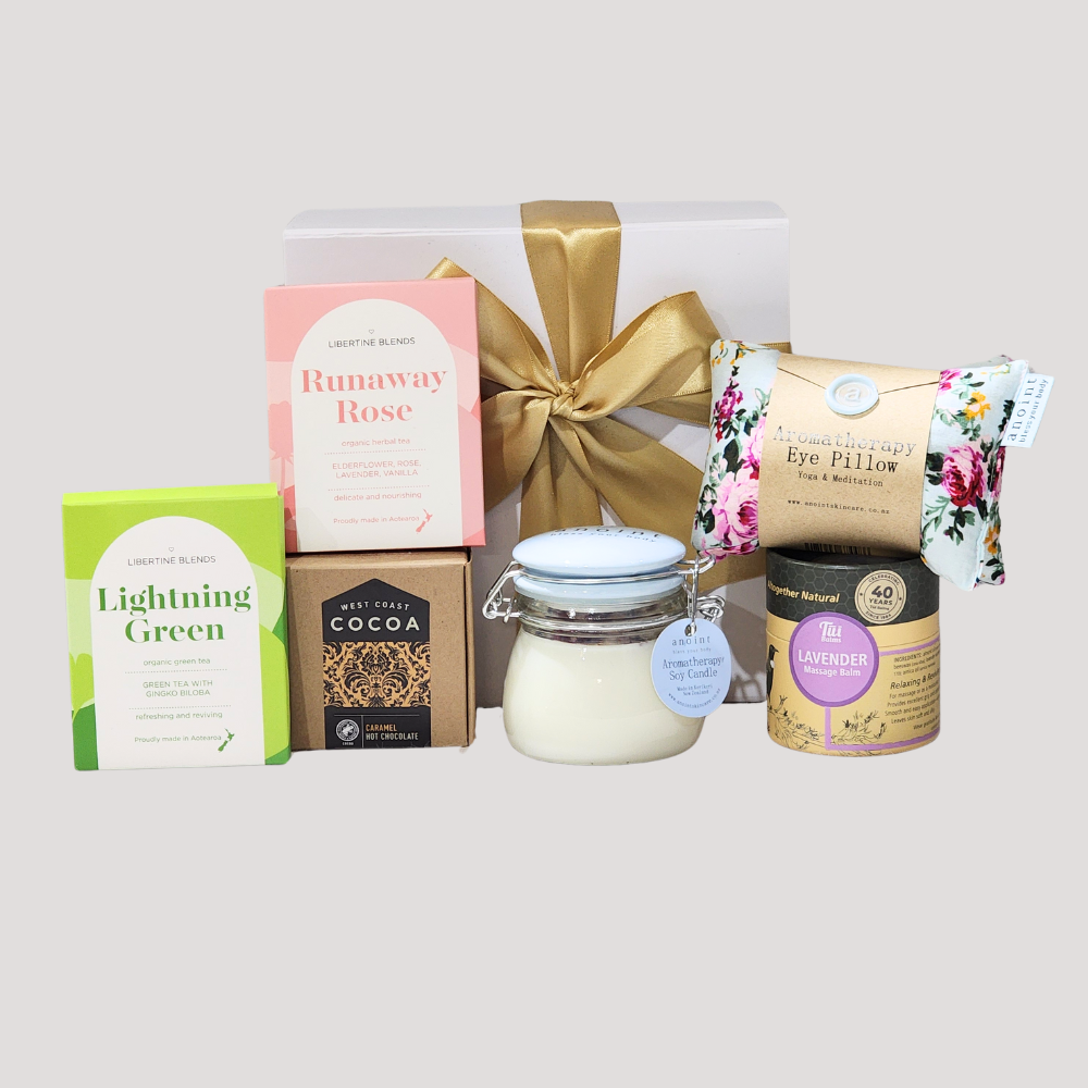 Comforting gift box with green tea, lavender balm, hot chocolate, candle, eye pillow, and rose tea for recovery.