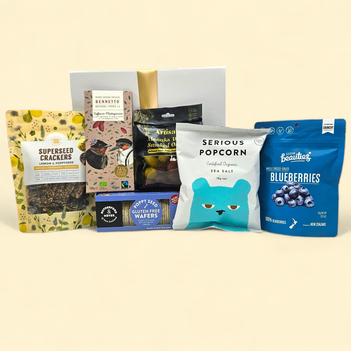 Gourmet gluten-free gift box with crackers, popcorn, olives, dark chocolate, blueberries, and pink peppercorn crackers.