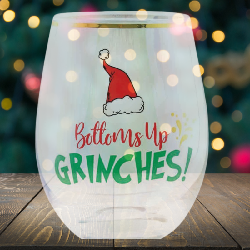 Stemless wine glass with "Bottoms Up Grinches" message, perfect for holiday toasts and adding humor to celebrations.