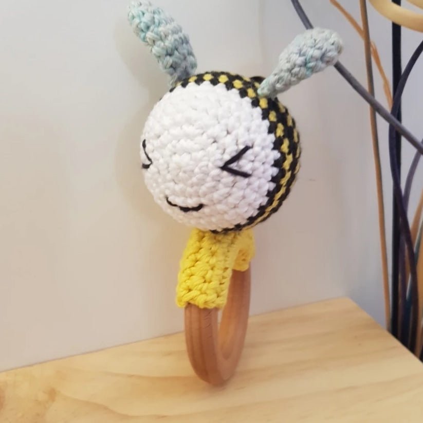 Bee-shaped rattle and teether made of cotton and beechwood, perfect for sensory play and teething relief.