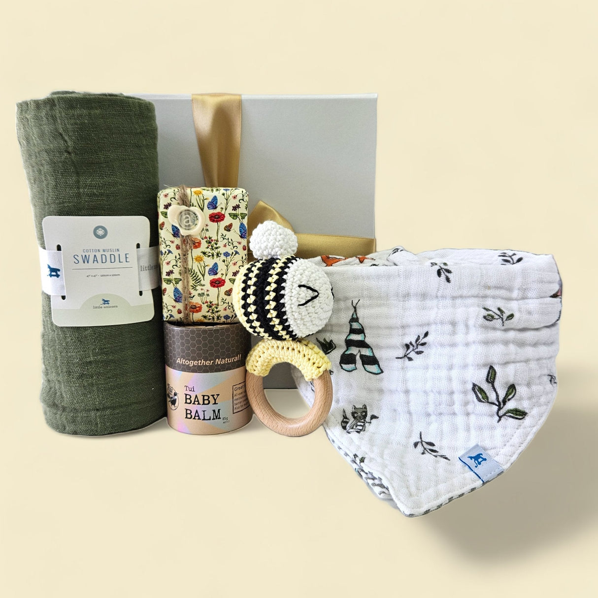 A beautifully curated gift box for newborns, featuring gentle essentials like a muslin swaddle, baby balm, and rattle.