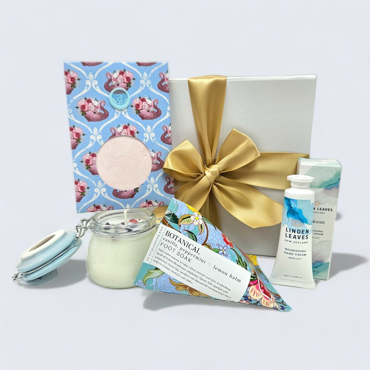 Gift box featuring relaxing aromatherapy candle, hand cream, facial mask, and soothing foot soak with elegant packaging.