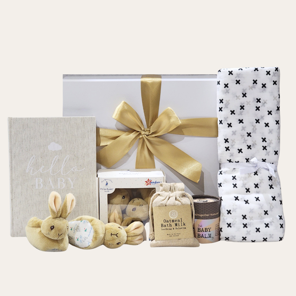 Elegant baby gift box featuring essentials like booties, balm, and a muslin blanket for welcoming a newborn with love.