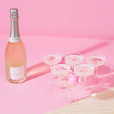 Prosecco Pong game set featuring 12 plastic glasses and 3 pink ping pong balls for trendy, bubbly party fun.