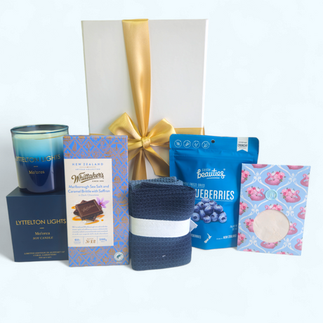 Elegant gift box featuring a curated selection of pampering items including a candle, facial mask, and chocolates.