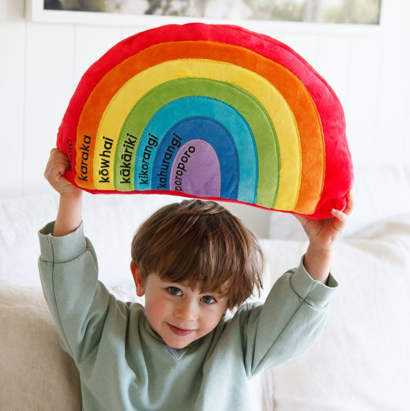 Soft rainbow cushion featuring Te Reo Maori and English colors, perfect for teaching kids while decorating their space.