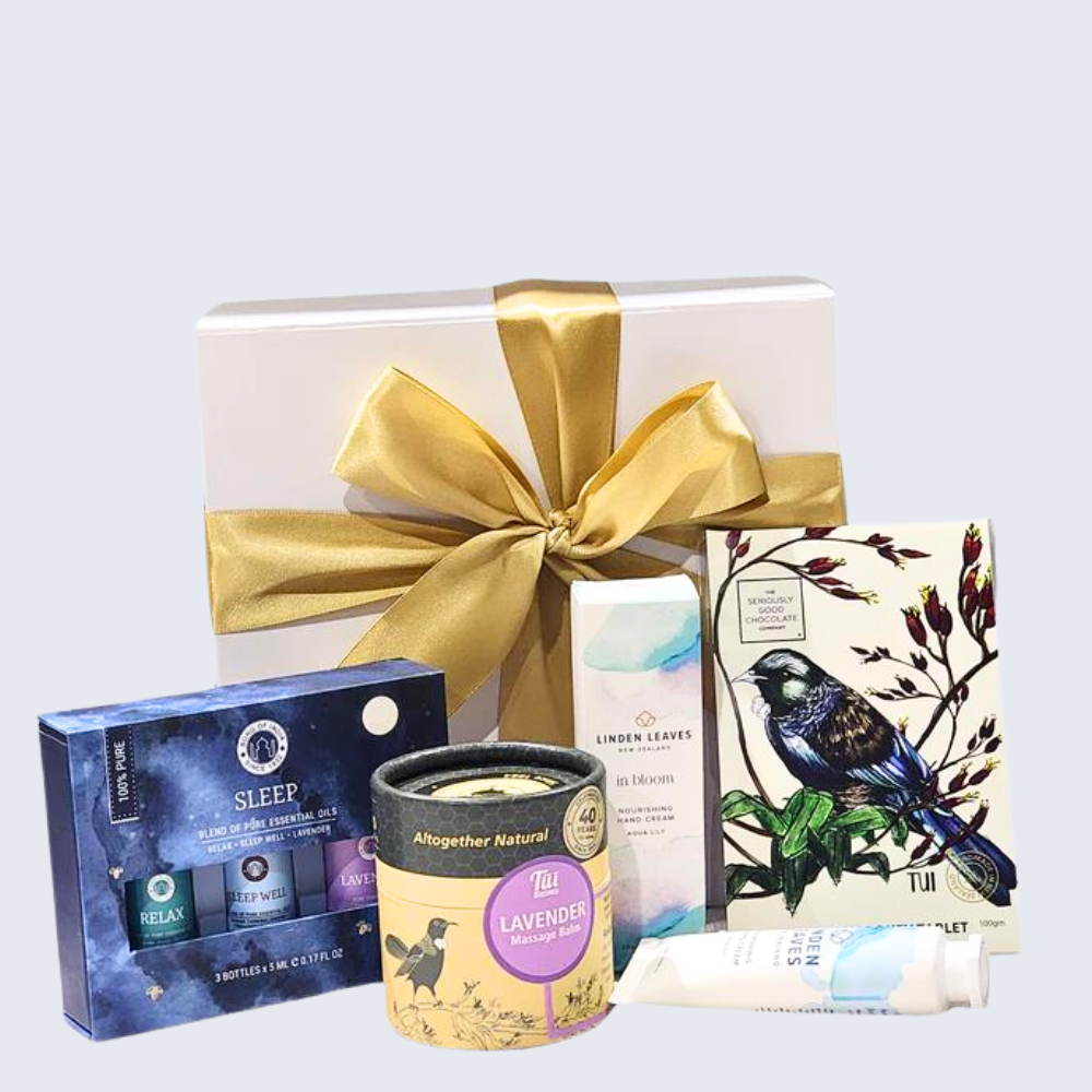 Elegant gift box featuring essential oils, lavender balm, hand cream, and chocolate for relaxation and self-care.