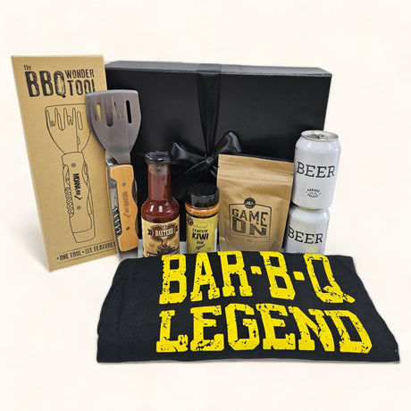 Gift box for BBQ lovers featuring premium beer, spices, sauce, apron, and a versatile grilling tool, beautifully presented.