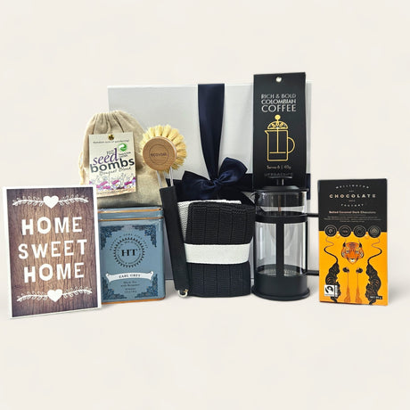 Home Sweet Home gift box featuring decor, gourmet tea, seed bombs, eco-friendly brushes, coffee, and indulgent chocolate.