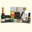 Gift box featuring champagne, gourmet snacks, organic cloths, and stylish kitchenware for new homeowners.